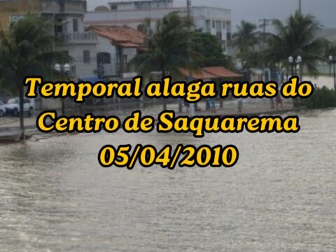Fotografia urbana mostrando a Rua Barão de Saquarema, no Centro de Saquarema, completamente alagada pela forte chuva de abril de 2010, com a água cobrindo o asfalto e calçadas próximas à lagoa.